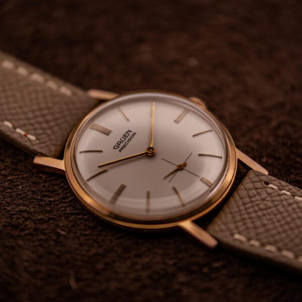 Vintage Gruen Precision 510 top-down view, cream dial and gold-plated front case on mud grey saffiano leather