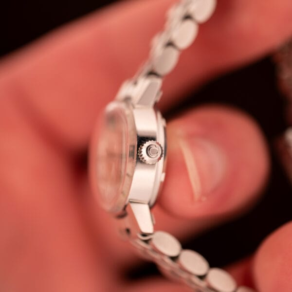 Side profile of Omega Ladymatic 566.002 stainless steel case showing the Omega-signed crown at 3 with original lug shape