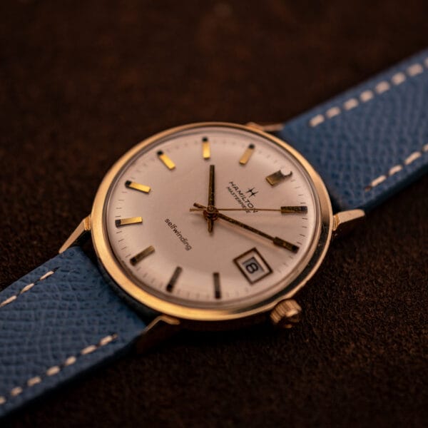 Hamilton Masterpiece 10k gold filled case at three-quarter angle with date window at three and applied baton indices
