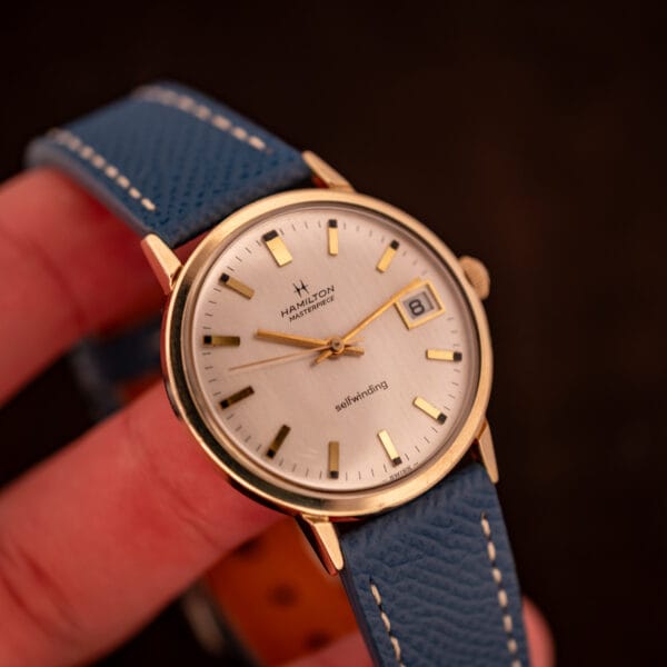 Vintage Hamilton Masterpiece automatic held in hand at an angle highlighting the warm yellow gold filled case and brushed dial