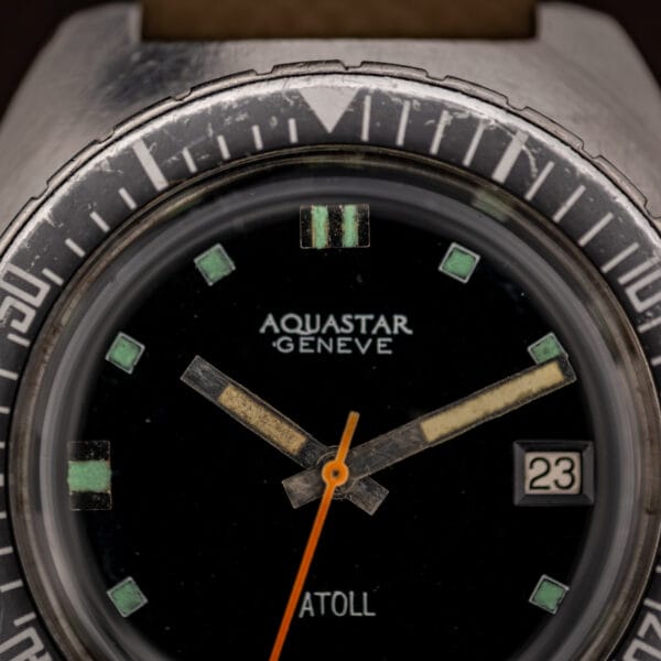 Aquastar Atoll 1001 matte black dial macro showing AQUASTAR GENEVE printing, aged green tritium square markers and pencil hands