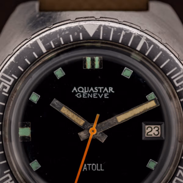 Aquastar Atoll 1001 matte black dial macro showing AQUASTAR GENEVE printing, aged green tritium square markers and pencil hands