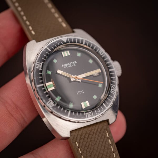 Aquastar Geneve Atoll Ref. 1001 in hand, dial and ghosted bezel visible against fingertips for scale