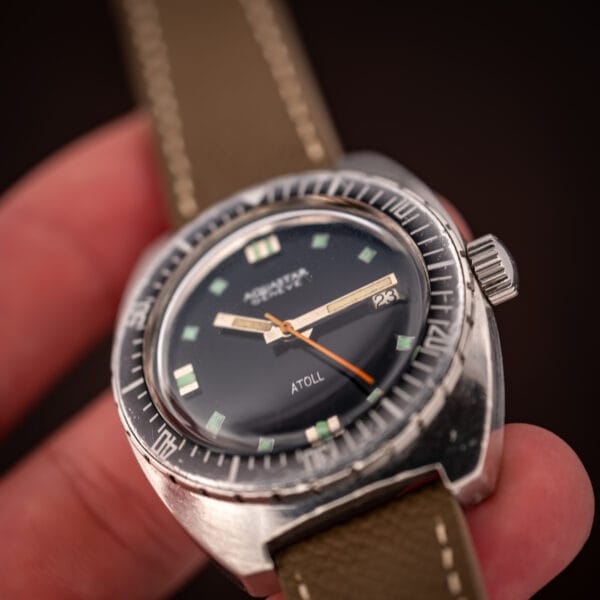Aquastar Atoll 1001 hand-held angled view with crown and ghosted dive bezel in focus