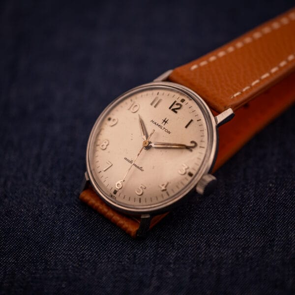 Hamilton Accumatic A-507 angled flatlay on navy linen highlighting silver textured dial finish