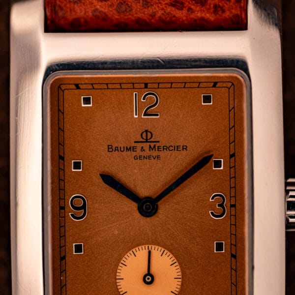 Baume & Mercier Hampton MV045063 copper dial close-up showing applied 12 and 3 Arabic numerals beneath the Phi-crest Geneve signature