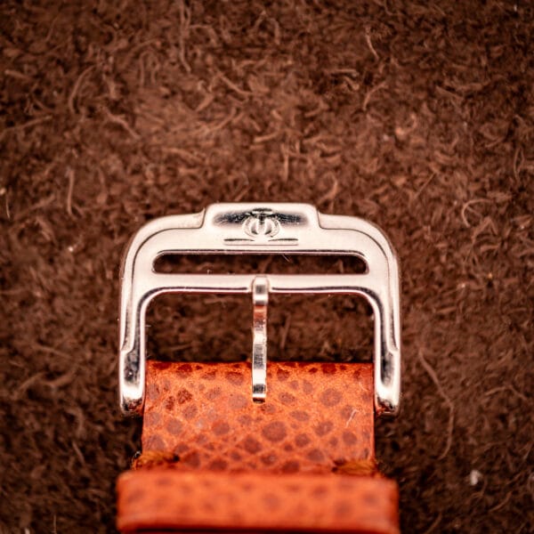 Baume & Mercier signed Phi-crest buckle on the original brown lizard leather strap, macro view