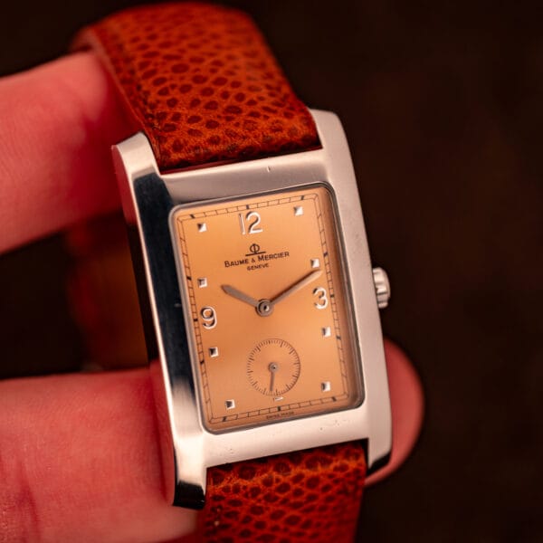 Baume & Mercier Hampton MV045063 held in hand showing rectangular tank proportions, copper dial, and curved lug architecture