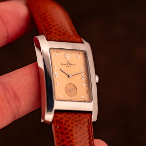Baume & Mercier Hampton MV045063 side profile in fingers showing the polished case flank, convex bezel, and crown position