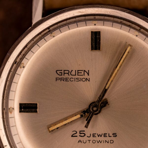 Gruen Precision dial center close-up showing GRUEN PRECISION signature and aged lume on dauphine hands