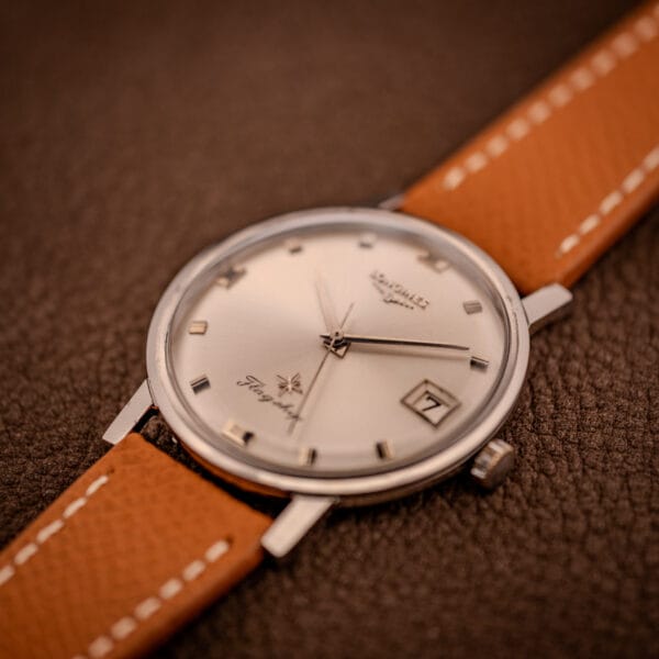 Vintage Longines Flagship 2821-285 angled three-quarter view with signed steel crown at three and date aperture against silver sunburst dial