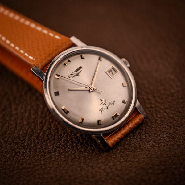 Longines Flagship 2821-285 in moody light, applied gold-tone baton markers catching across the silver sunburst dial