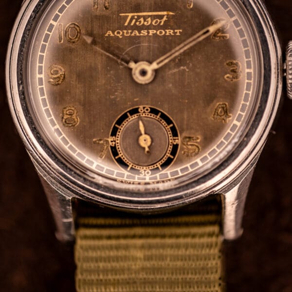 Tissot Aquasport tropical dial macro showing gilt printed Tissot signature, AQUASPORT wordmark, and outer black minute track