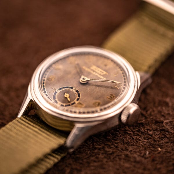 Tissot Aquasport WWII era stainless steel case angled three-quarter view on olive canvas NATO strap