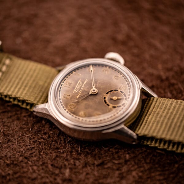 Tissot Aquasport on canvas strap photographed angled, showing stepped bezel and slim 28mm stainless steel case profile