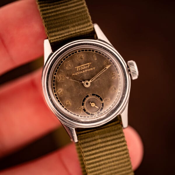 Tissot Aquasport tropical dial held in hand, gilt Arabic numerals and sub-seconds register visible above SWISS MADE printing