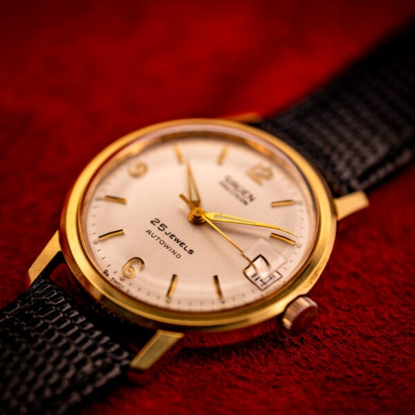 Vintage Gruen Precision angled three-quarter shot, gold-tone case, silver sunburst dial, date aperture at three, original crown