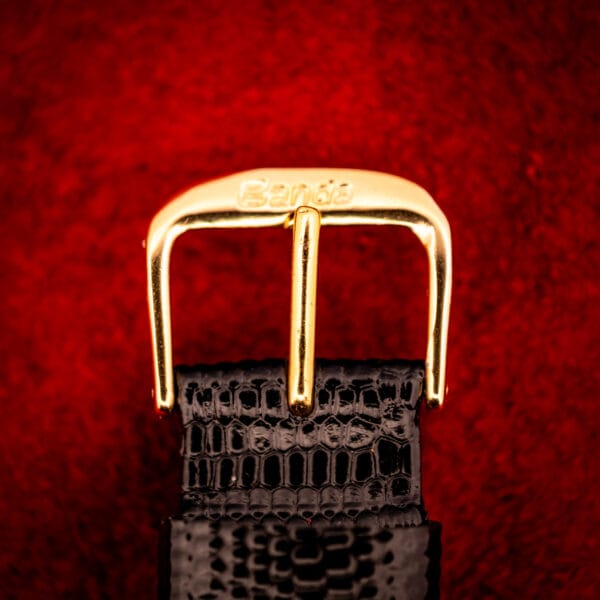 Vintage Gruen Precision strap and buckle close-up, black lizard-grain leather with gold-tone signed pin buckle
