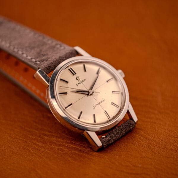 Omega Seamaster 135.005 stainless steel case three-quarter view with the gray Italian suede strap wrapping the spring bars