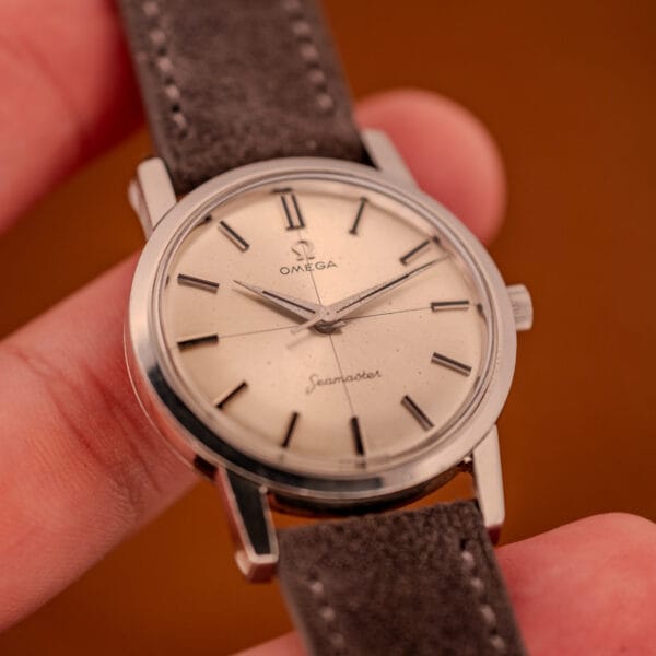 Omega Seamaster 135.005 in hand showing the 33.5mm dress proportions of the case and the gray suede strap