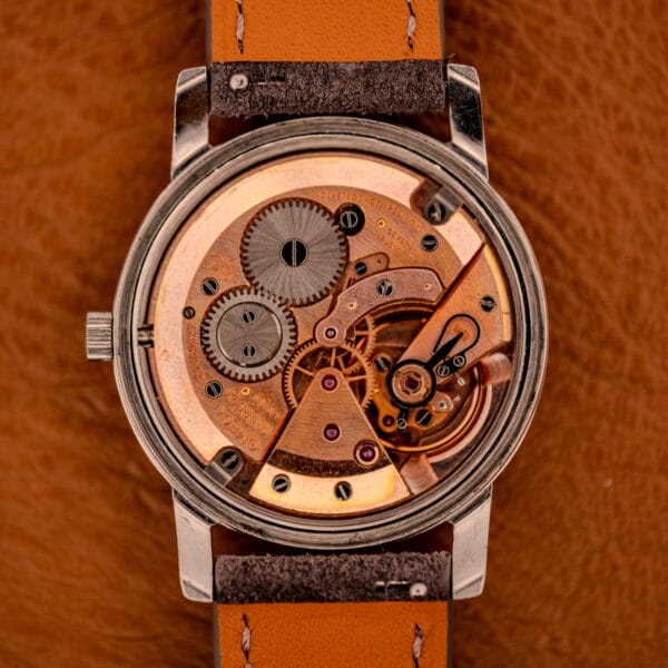 Omega caliber 600 manual-wind movement view with copper-toned bridges, swan-neck regulator, and the Omega logo stamped on the bridge
