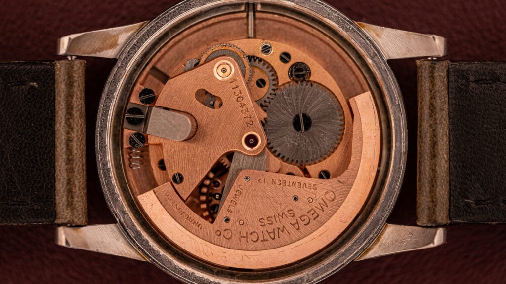Close-up view of the mechanical movement inside an Omega wristwatch, showcasing its intricate bumper movement with visible gears and detailed engravings.