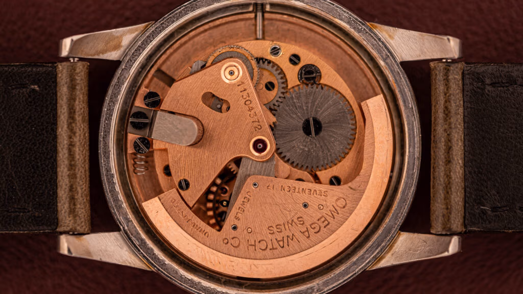 Close-up view of the mechanical movement inside an Omega wristwatch, showcasing its intricate bumper movement with visible gears and detailed engravings.