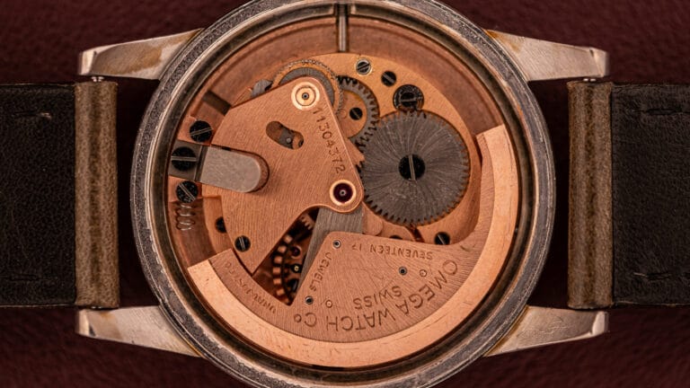 Close-up view of the mechanical movement inside an Omega wristwatch, showcasing its intricate bumper movement with visible gears and detailed engravings.