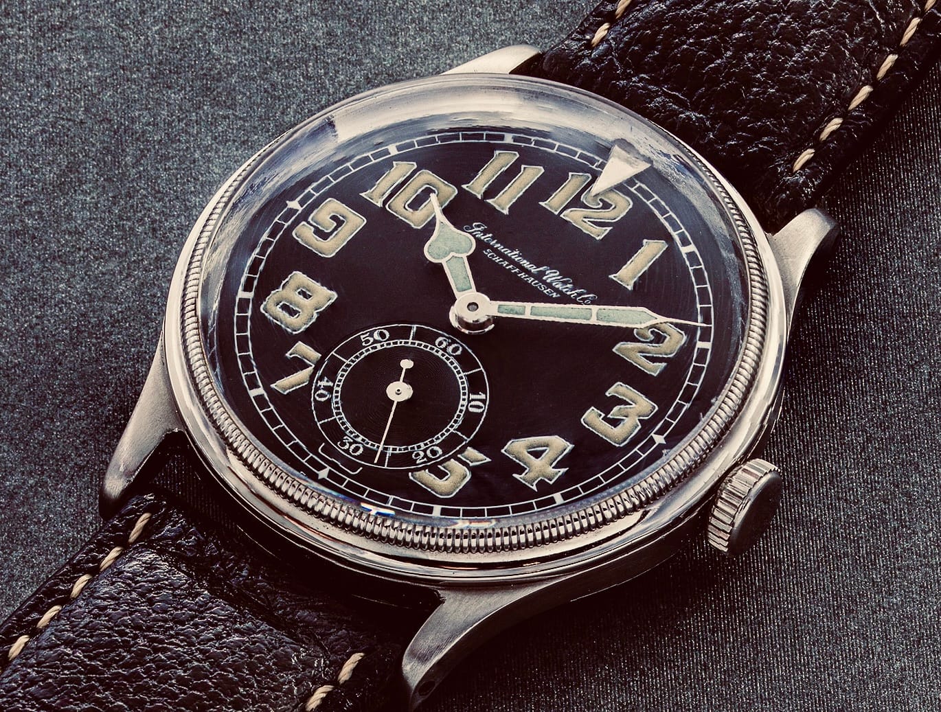 Vintage field watch with a black dial, large luminous numerals, and a worn black leather strap—reminiscent of classic dirty dozen watches.