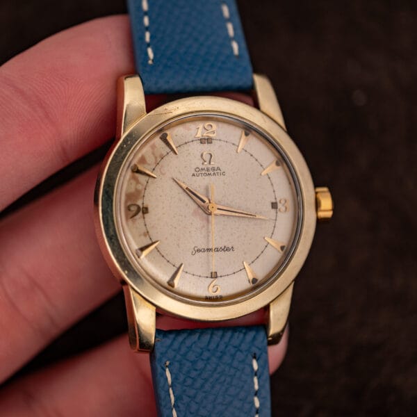 Omega Seamaster bumper 2577-19 held in hand, gold-capped case and eggshell dial front view