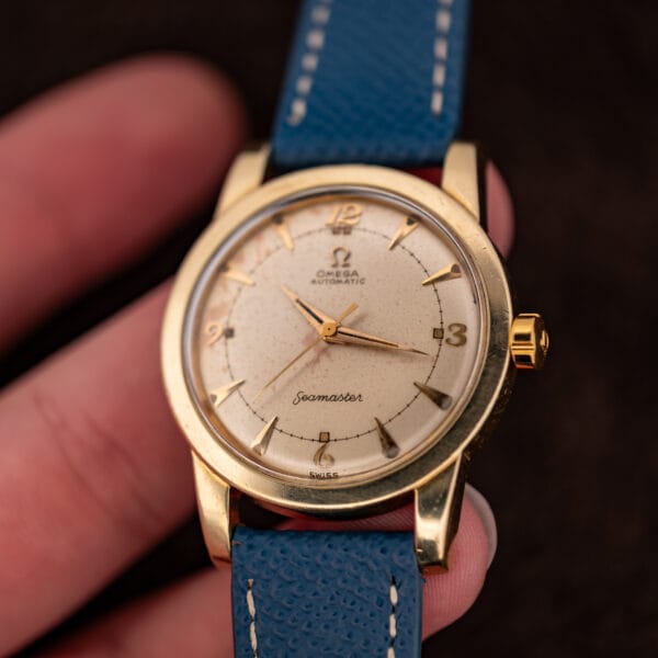 Omega Seamaster 2577-19 in hand at an angle, signed crown and aged eggshell dial