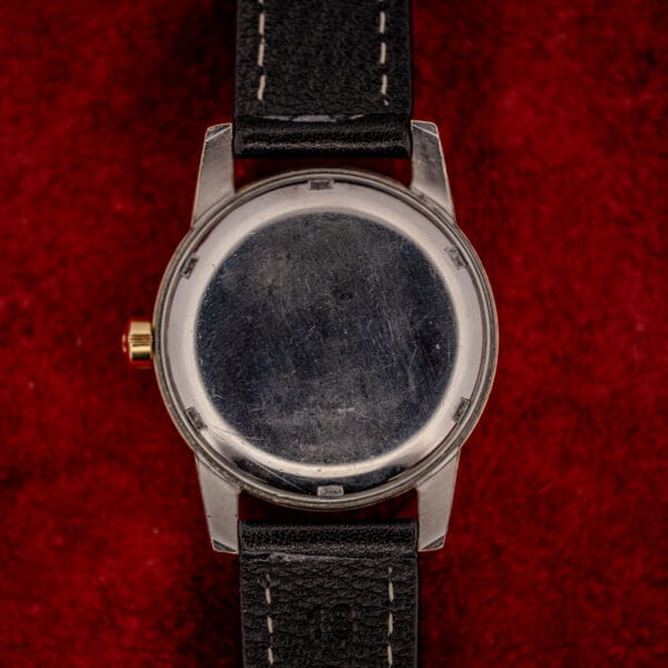 Omega Seamaster stainless steel snap caseback with honest swirled wear and the gold signed crown at left