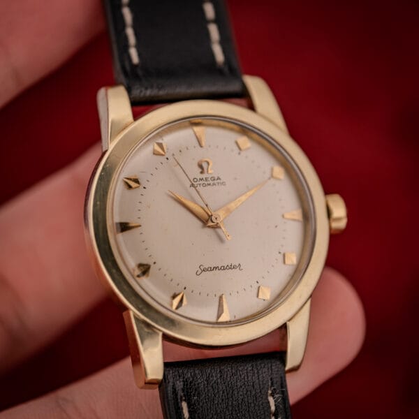 Omega Seamaster bumper ref. 2577-22 held in hand showing gold-capped case, cream dial and faceted dart markers