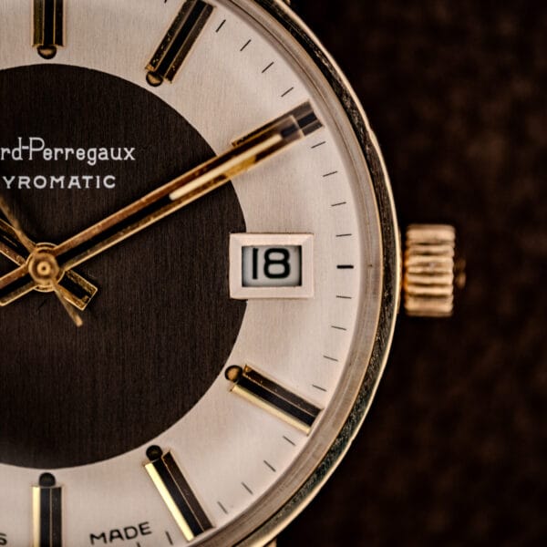 Girard-Perregaux Gyromatic framed date window at three beside the fluted gold-tone crown