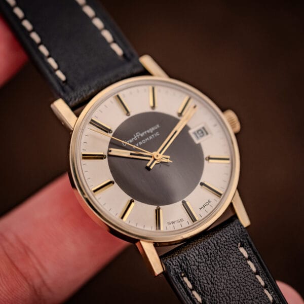 Vintage Girard-Perregaux Gyromatic gold-filled dress watch held in hand on a black leather strap with contrast stitching