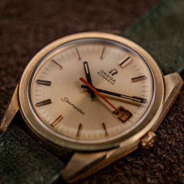 Omega Seamaster 166.028 gold-capped case at an angle, champagne sunburst dial and orange seconds hand