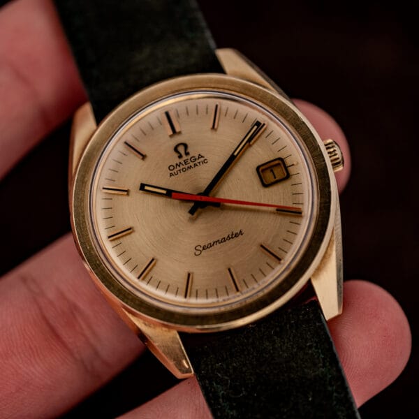 Vintage Omega Seamaster 166.028 in hand showing the gold cap case, signed crown and orange center seconds hand