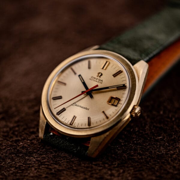 Omega Seamaster 166.028 gold cap three-quarter view on forest green suede strap with tan leather lining