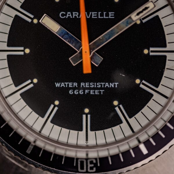 Caravelle 666 Feet dial macro showing CARAVELLE signature, steel baton hands and aged cream lume plots