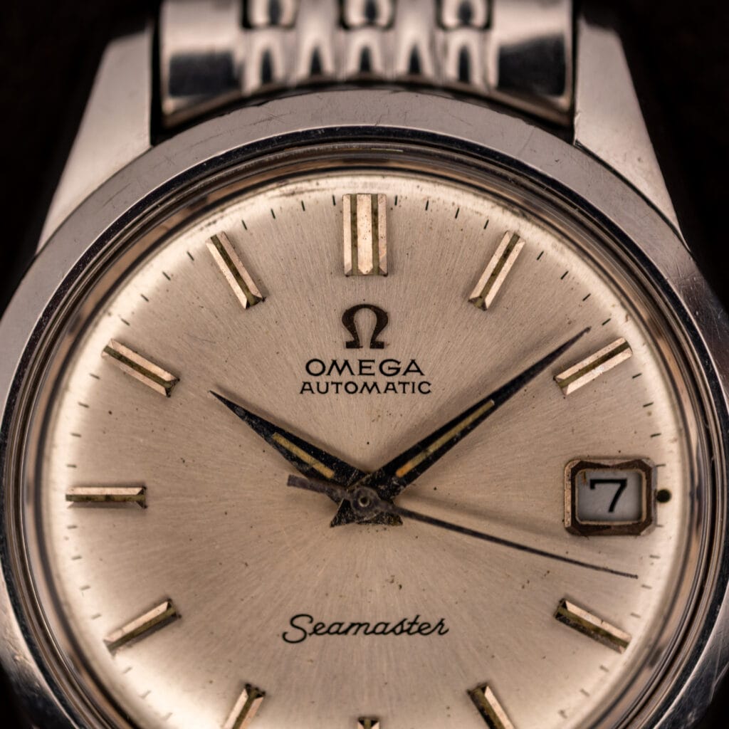Omega Seamaster 166.010 silver dial close-up showing applied baton markers and date window at three