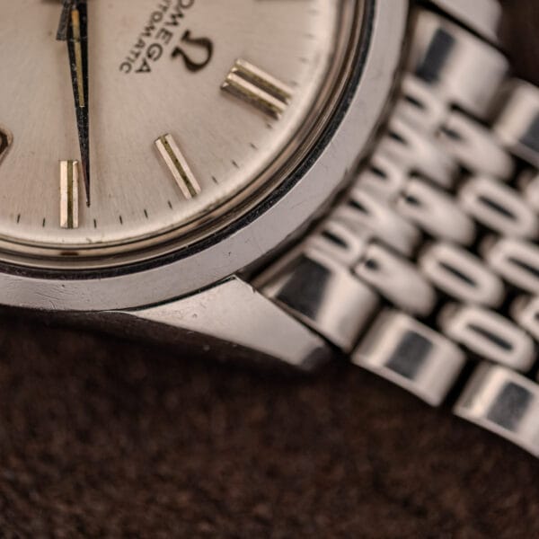 Omega Seamaster 166.010 applied baton markers and faceted case edge beside a beads-of-rice bracelet