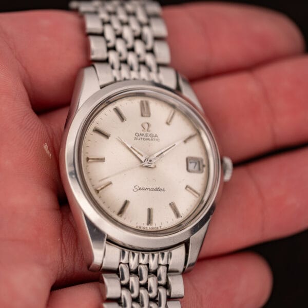 Omega Seamaster 166.010 in hand at an angle, dauphine hands over silver dial with Seamaster script