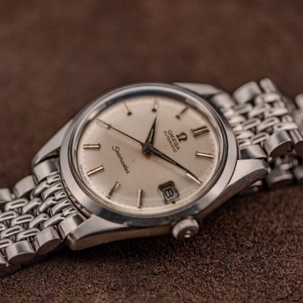 Omega Seamaster 166.010 silver dial and steel case at an angle on a beads-of-rice bracelet