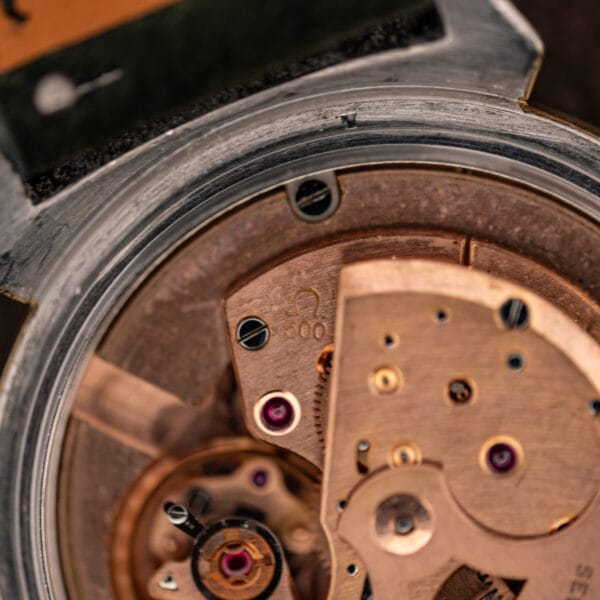 Omega caliber 500 bridge close-up showing the Omega symbol and 500 caliber stamp with ruby jewels