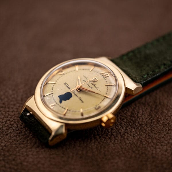 Omega Seamaster 14363-1 SC gold-capped hooded lug case held in hand on a dark green suede strap