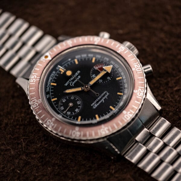 Wittnauer 7004A Professional Chronograph at an angle showing arrow hands, salmon bezel and a silver steel bracelet