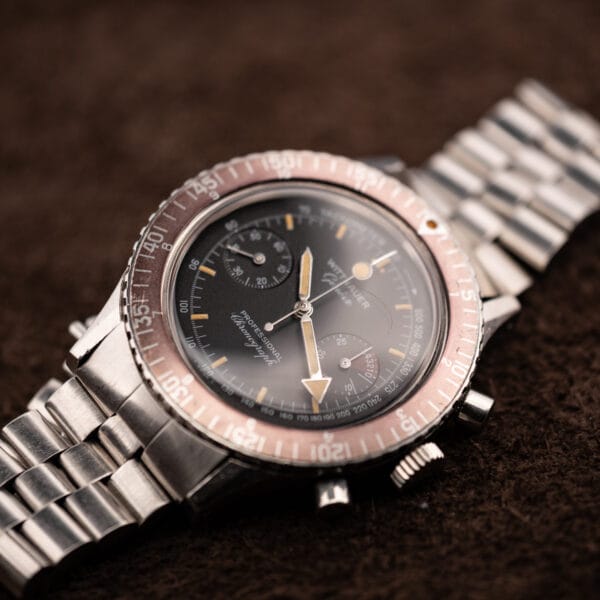 Wittnauer Professional Chronograph 7004A glamour shot with faded cherry-red regatta bezel and beads-of-rice bracelet on brown suede