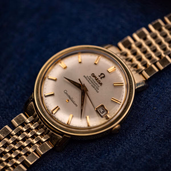 Vintage Omega Constellation 168.004 angled on blue, gold-capped case with silver chronometer dial and gold-filled bracelet