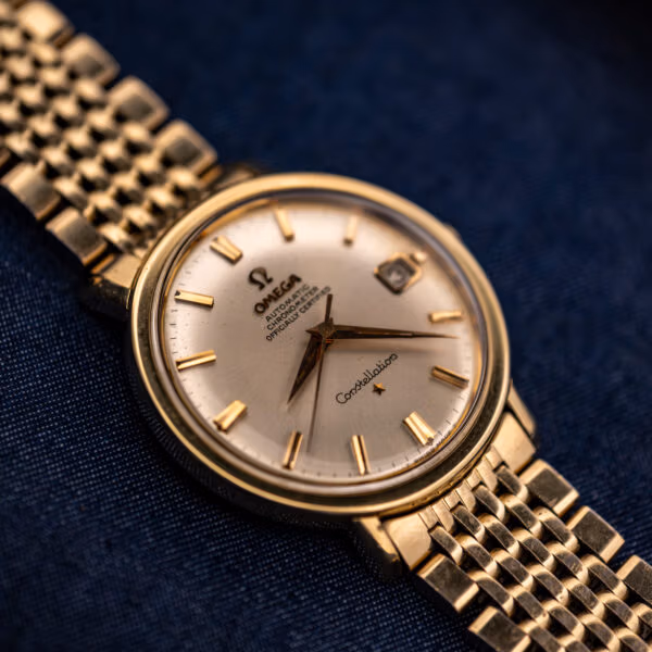 Omega Constellation 168.004 angled view of faceted lugs, silver dial, and gold beads-of-rice bracelet