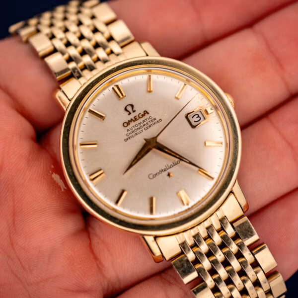 Vintage Omega Constellation 168.004 held in hand, silver chronometer dial and gold-filled beads-of-rice bracelet